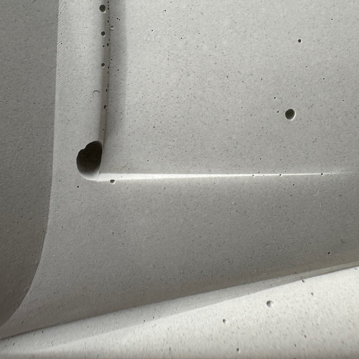 Pinholes and a mold mark along the edge of a cured concrete panel